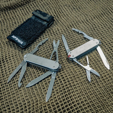 Two titanium 58 mm <i>TiSAKs</i> by @mpdwaberlin, a Victorinox Vagabond (long out of production) on the left, and a Rambler on the right. Custom sleeve to go with it